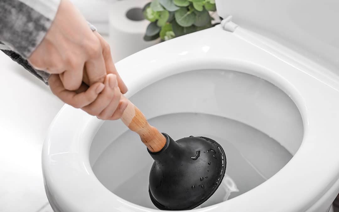 Turbo Plumbing & Rooter in Granada Hills - Young woman using plunger to unclog a toilet bowl