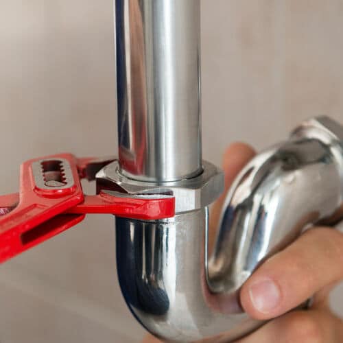 A Plumber Uses Wrench to Adjust Pipe.